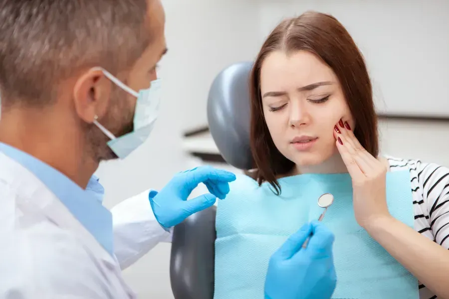A woman is sitting in a dental chair with a toothache.