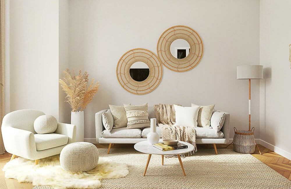 A living room with a couch , chair , coffee table and two mirrors on the wall.
