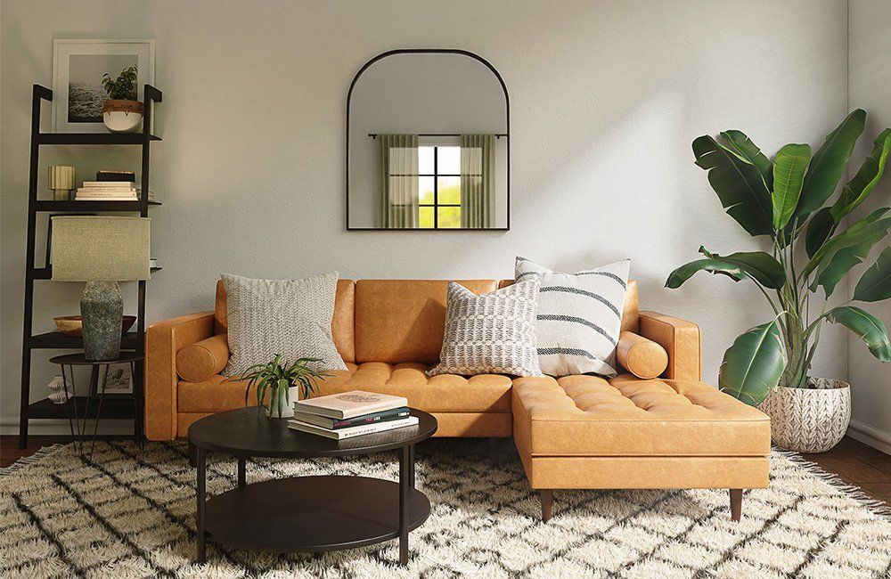 A living room with a couch , coffee table , and mirror.