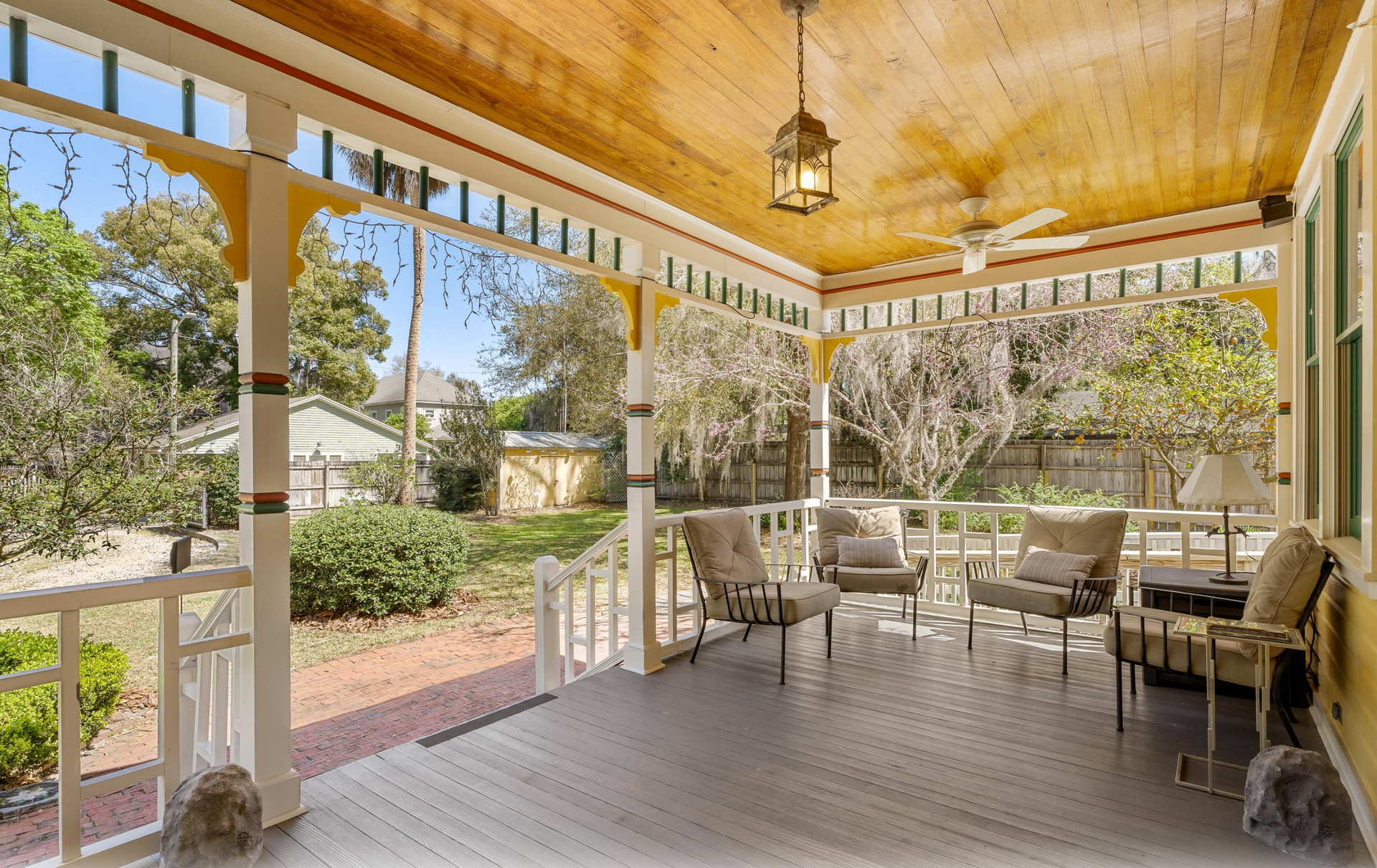 Covered porch at a yellow Victorian home.
