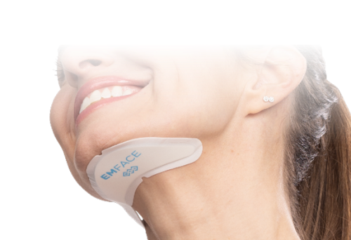 A woman is smiling while wearing a device on her neck.