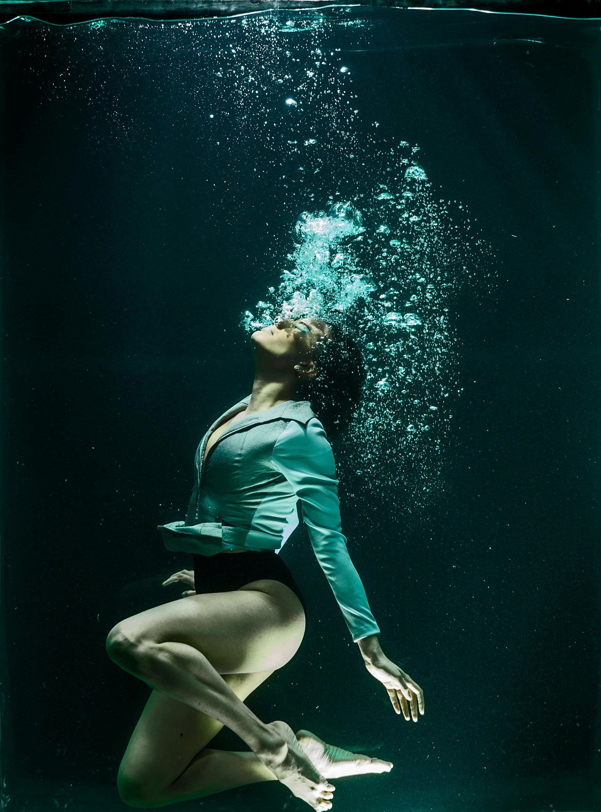 A woman is swimming underwater with bubbles coming out of her mouth.