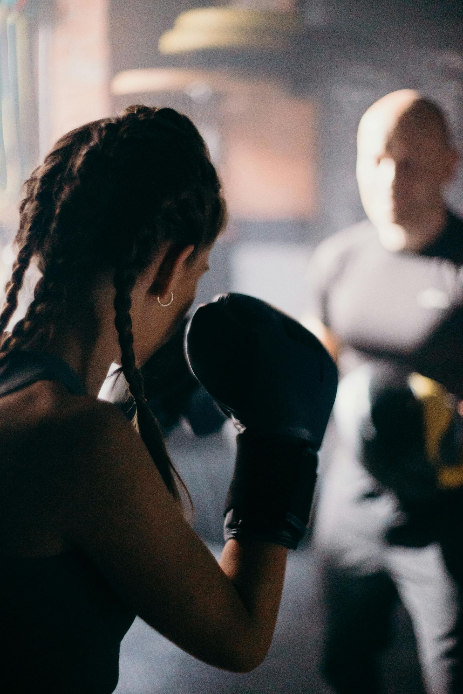 A woman wearing boxing gloves is standing in front of a man wearing boxing gloves.