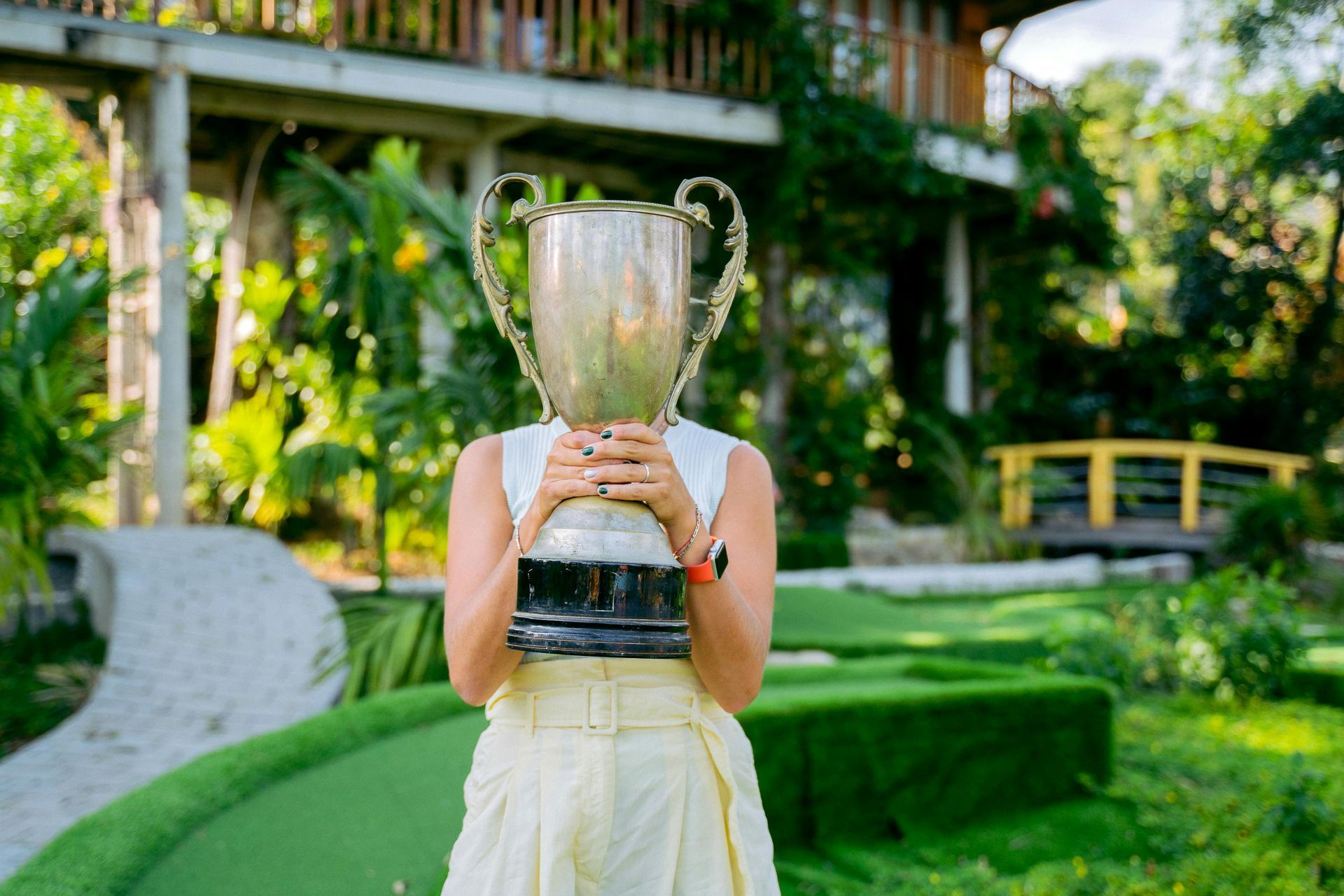 A woman is holding a trophy in front of her face.