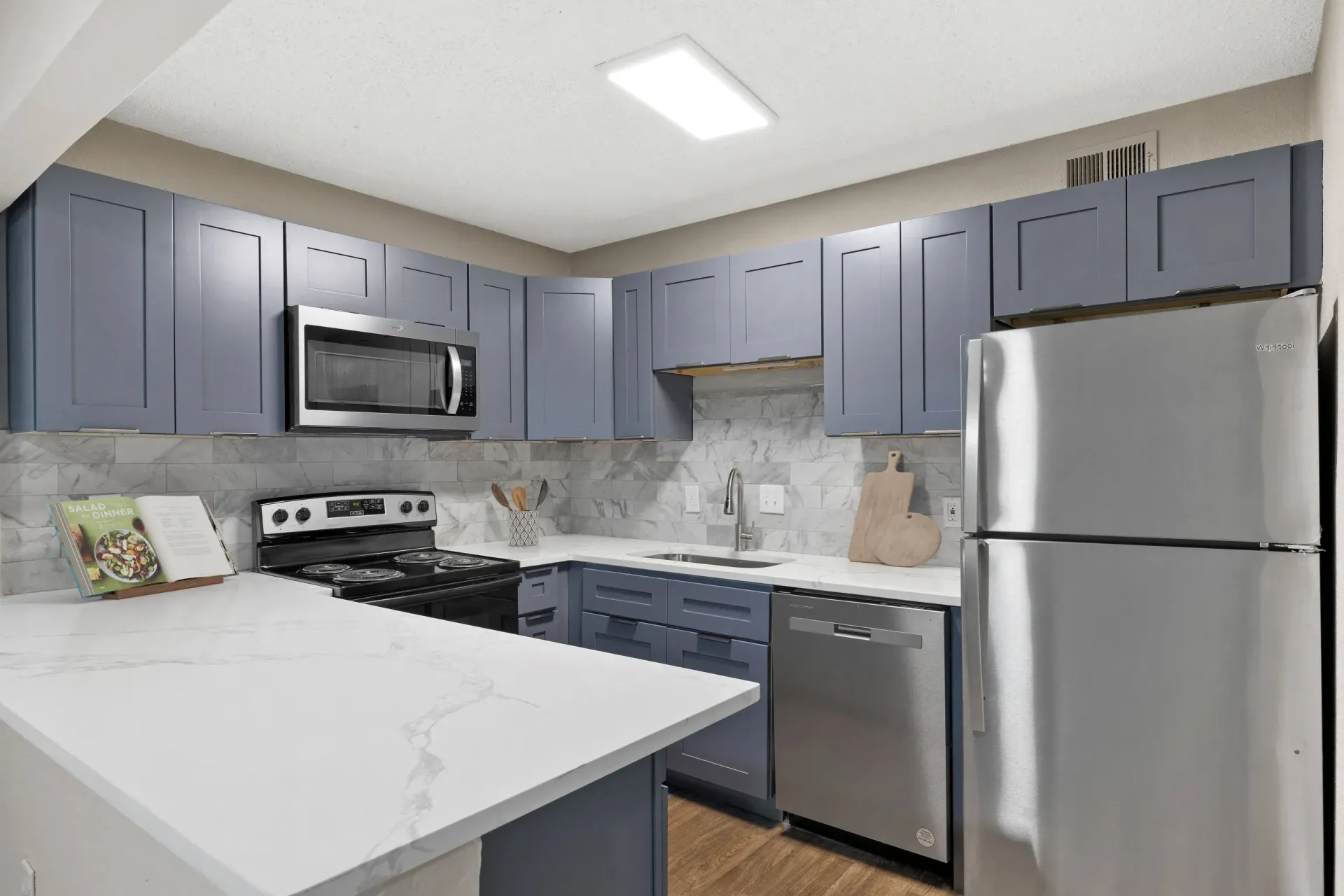 Modern kitchen with blue cabinets, stainless steel appliances, and white countertops at Mill House at East Cobb offers townhomes in East Cobb, GA.