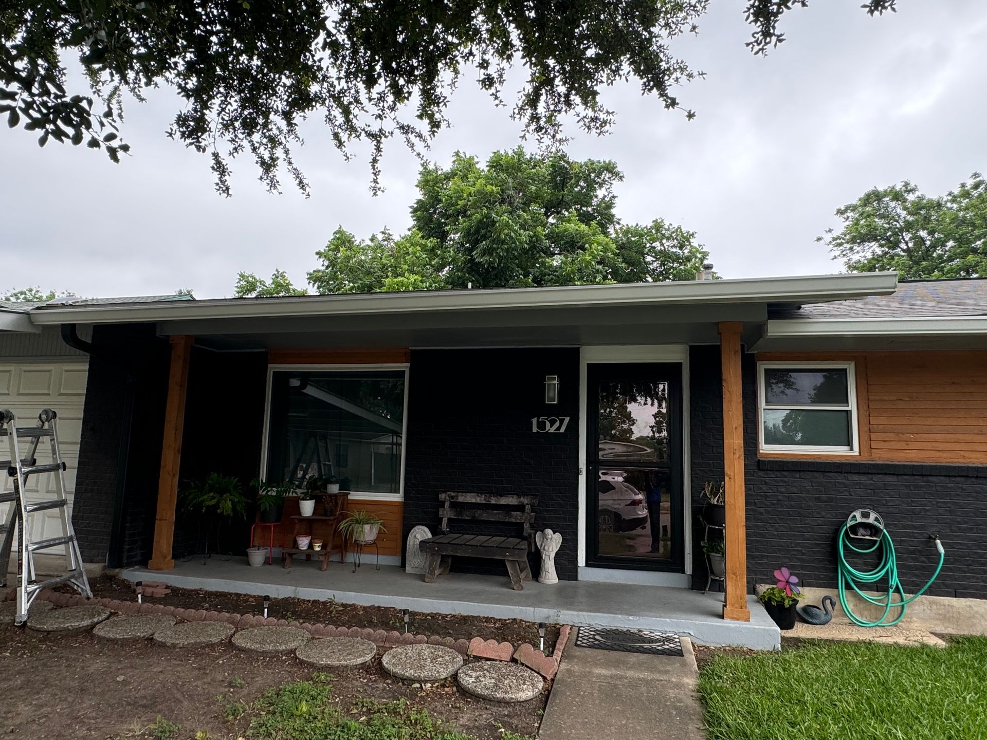 A house with a porch and a hose in front of it.