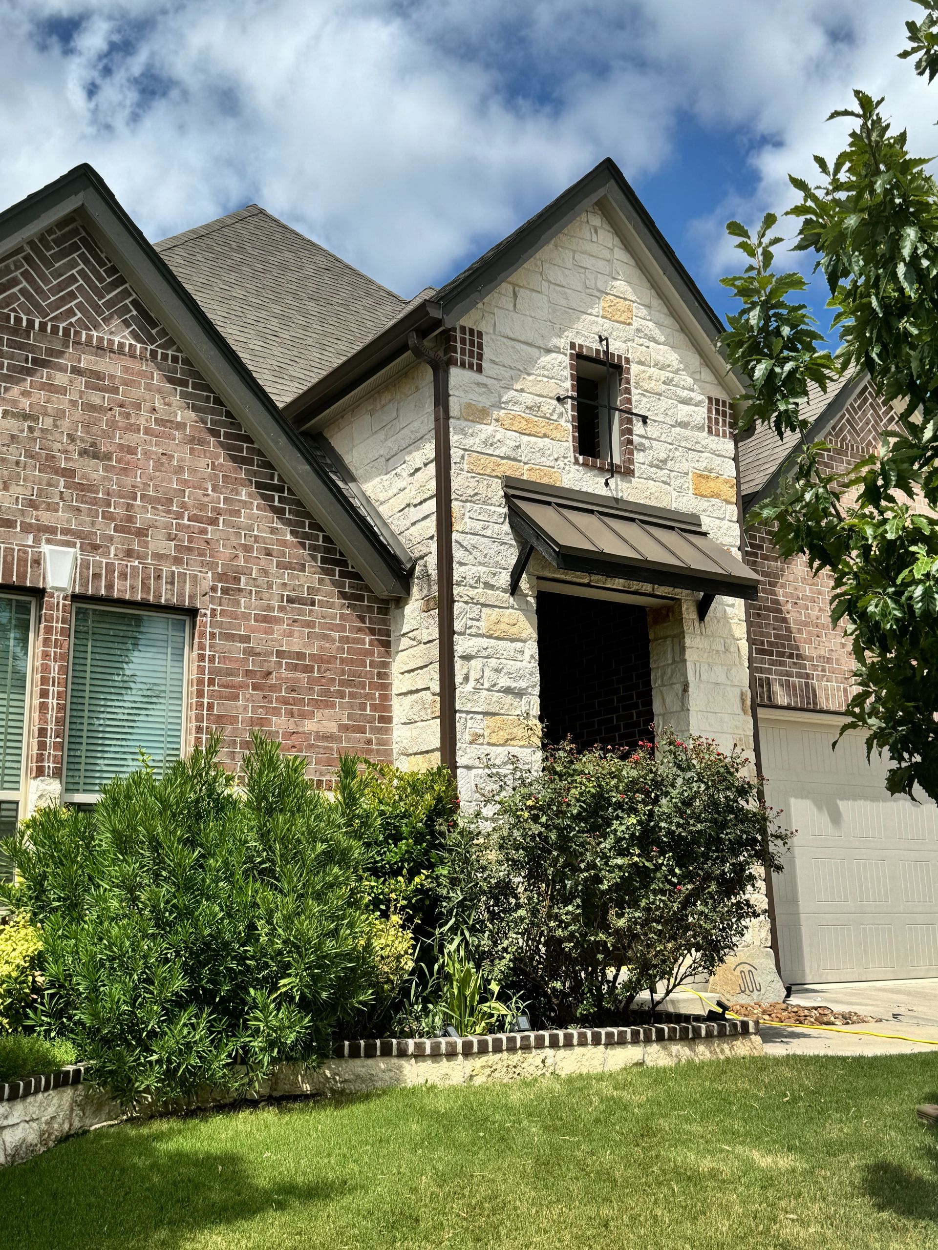 A brick and stone house with a large lawn in front of it