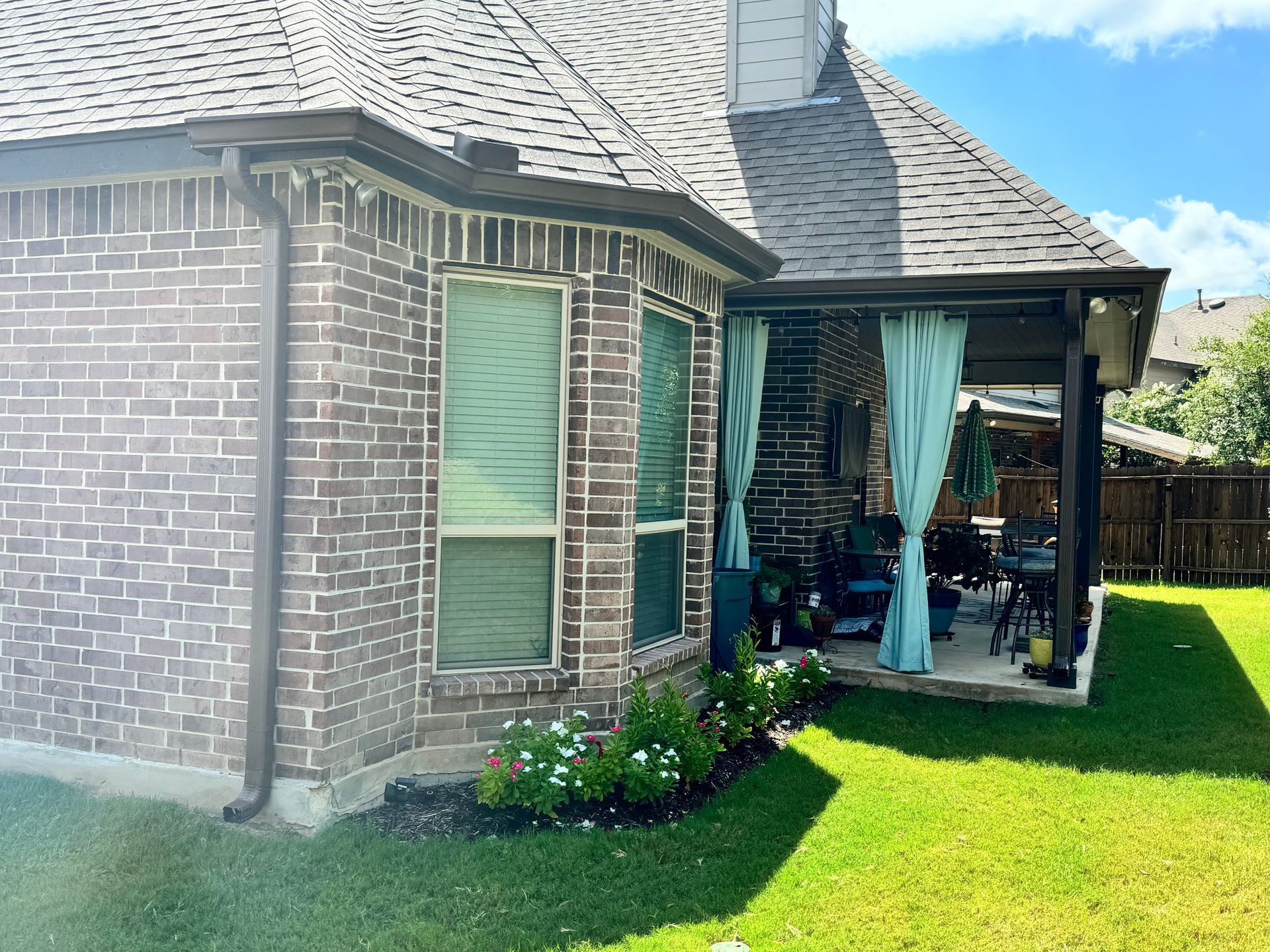 A brick house with a porch and a patio in the backyard.