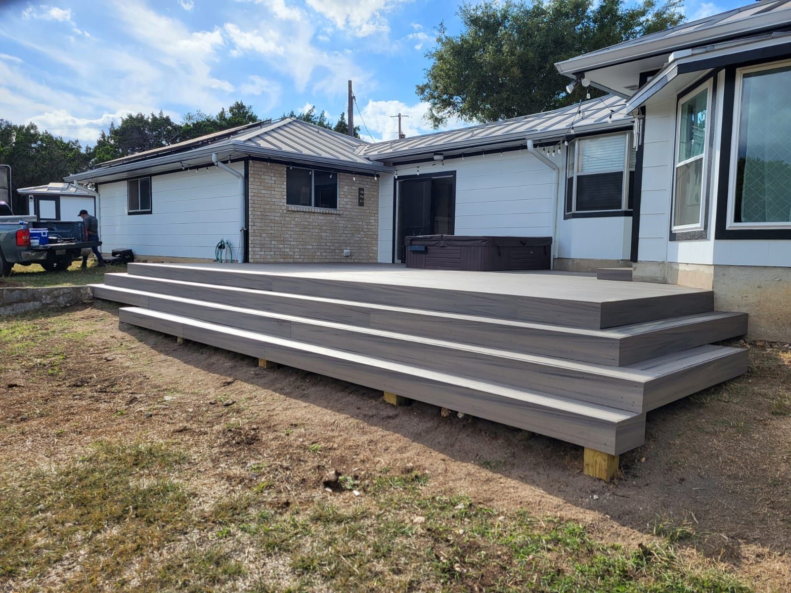 A white house with a large deck and stairs in front of it.