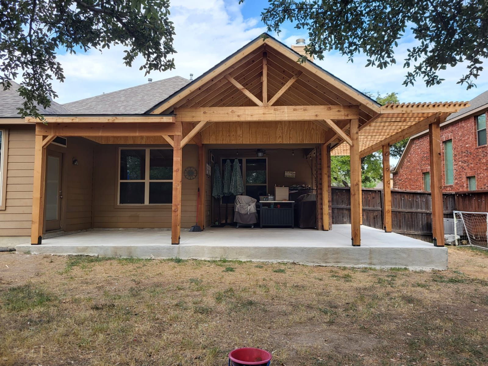 The back of a house with a wooden pergola on top of it.