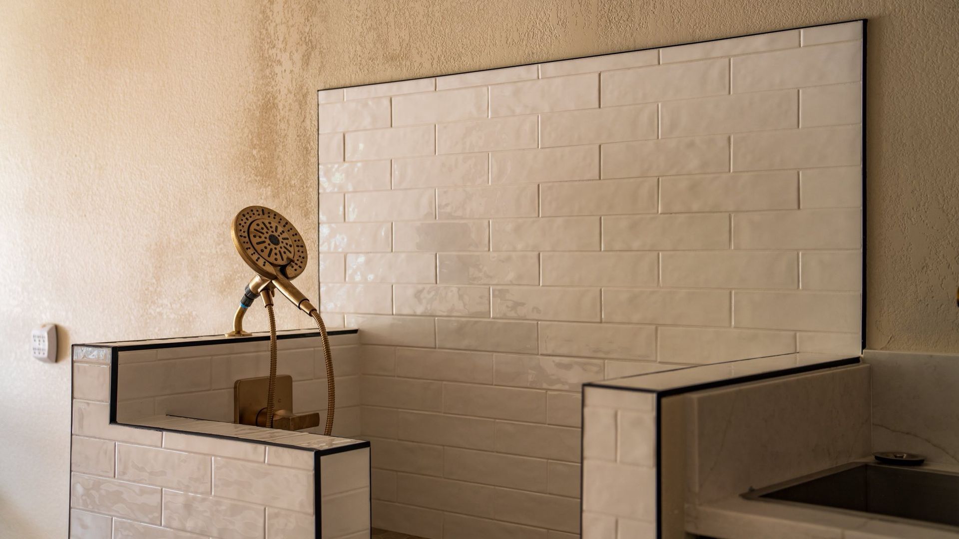 White tiled backsplash and sink area with a decorative metal object against a light-colored wall.