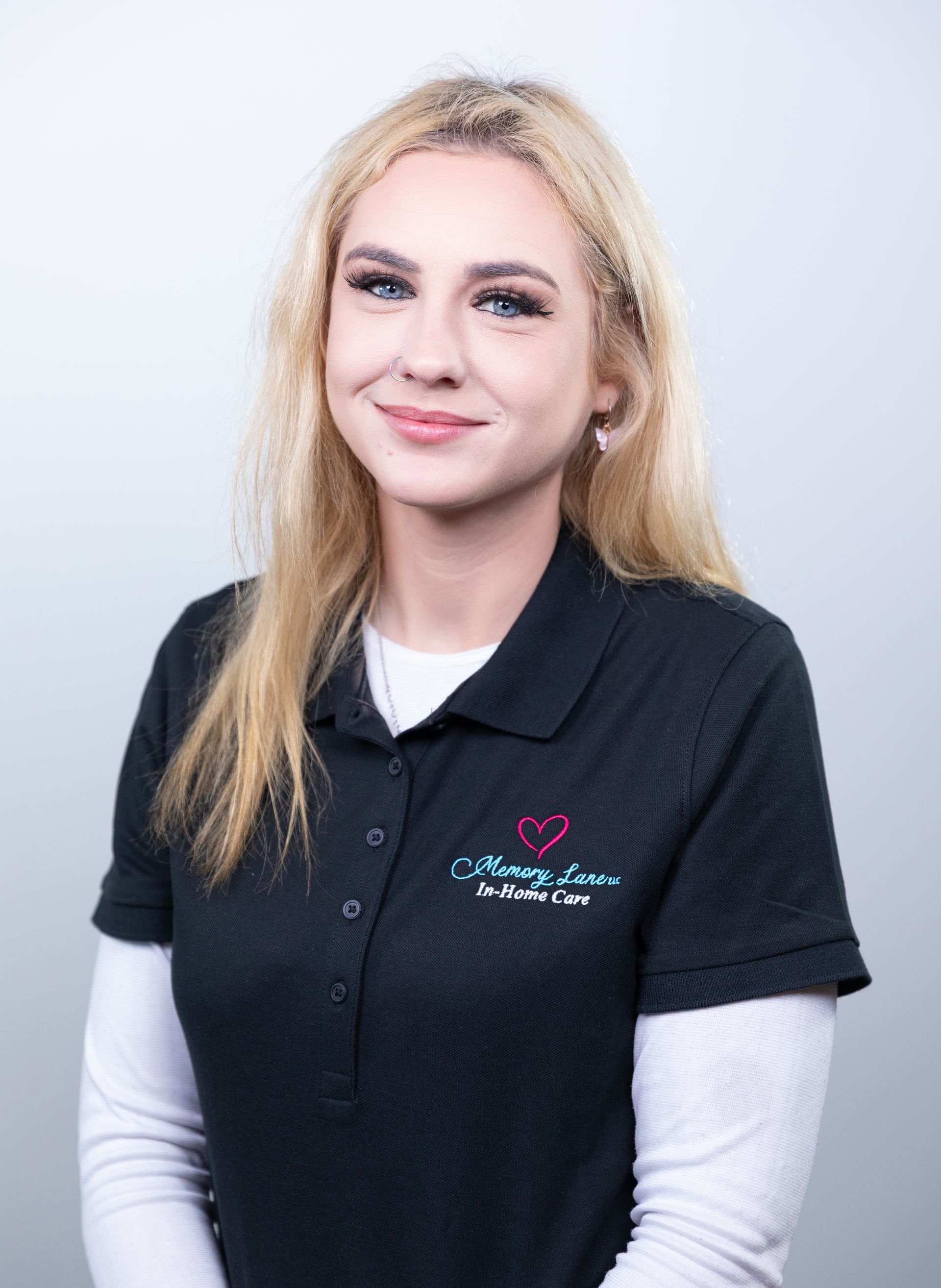 Woman with blonde hair wearing a black polo shirt smiling.
