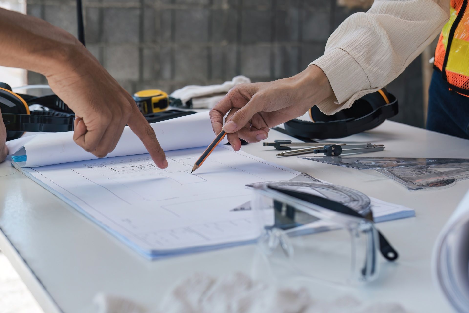 A couple of people are sitting at a table looking at a blueprint.