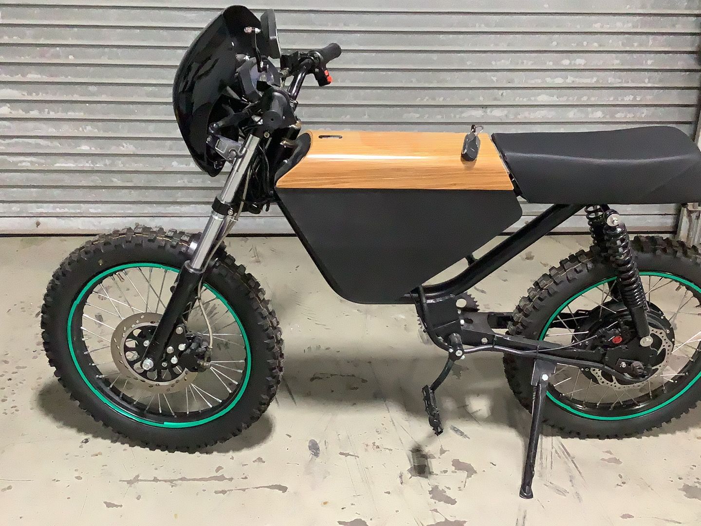 An electric motorcycle is parked in front of a garage door.