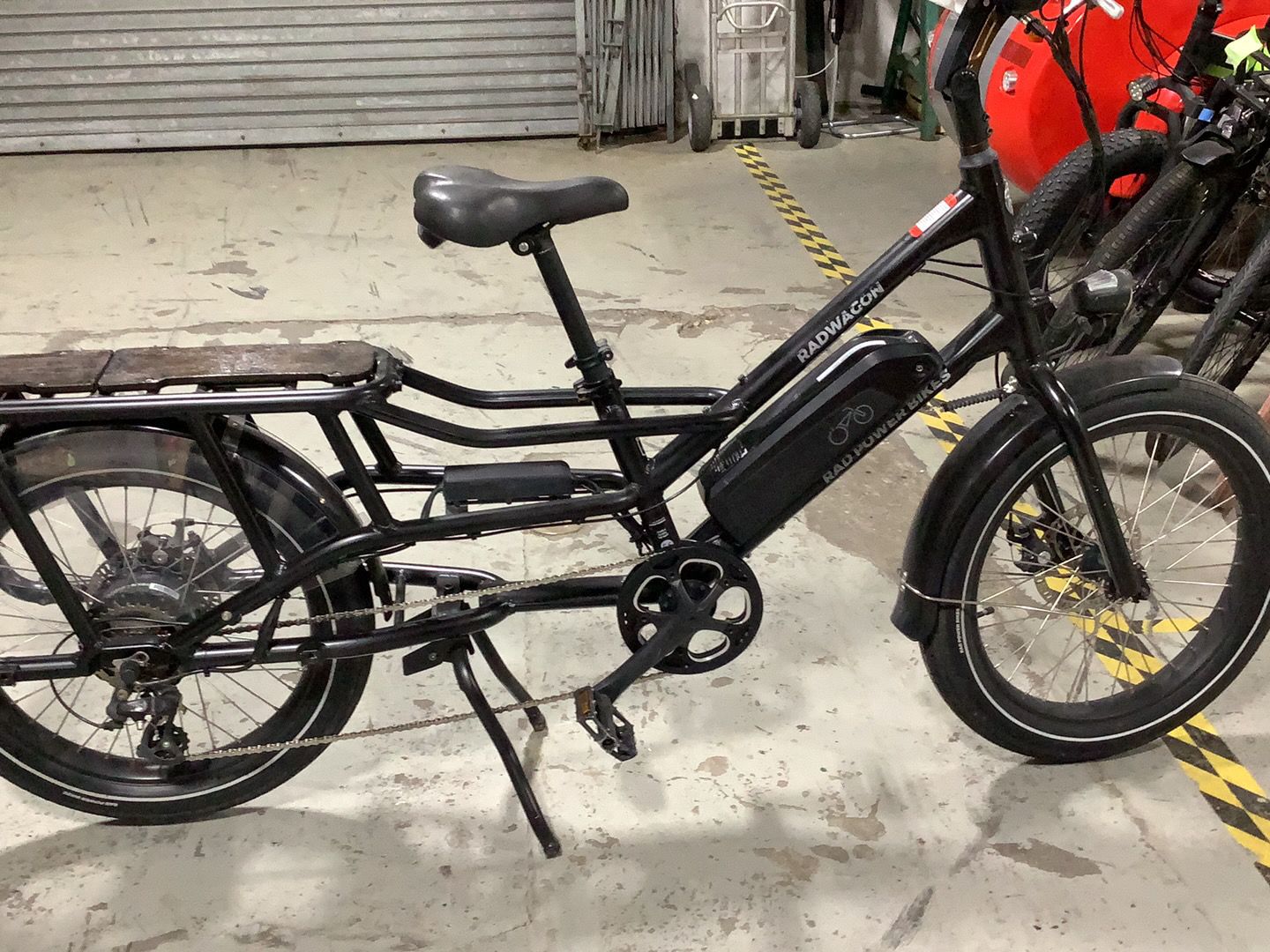 A black cargo bike is parked in a garage.