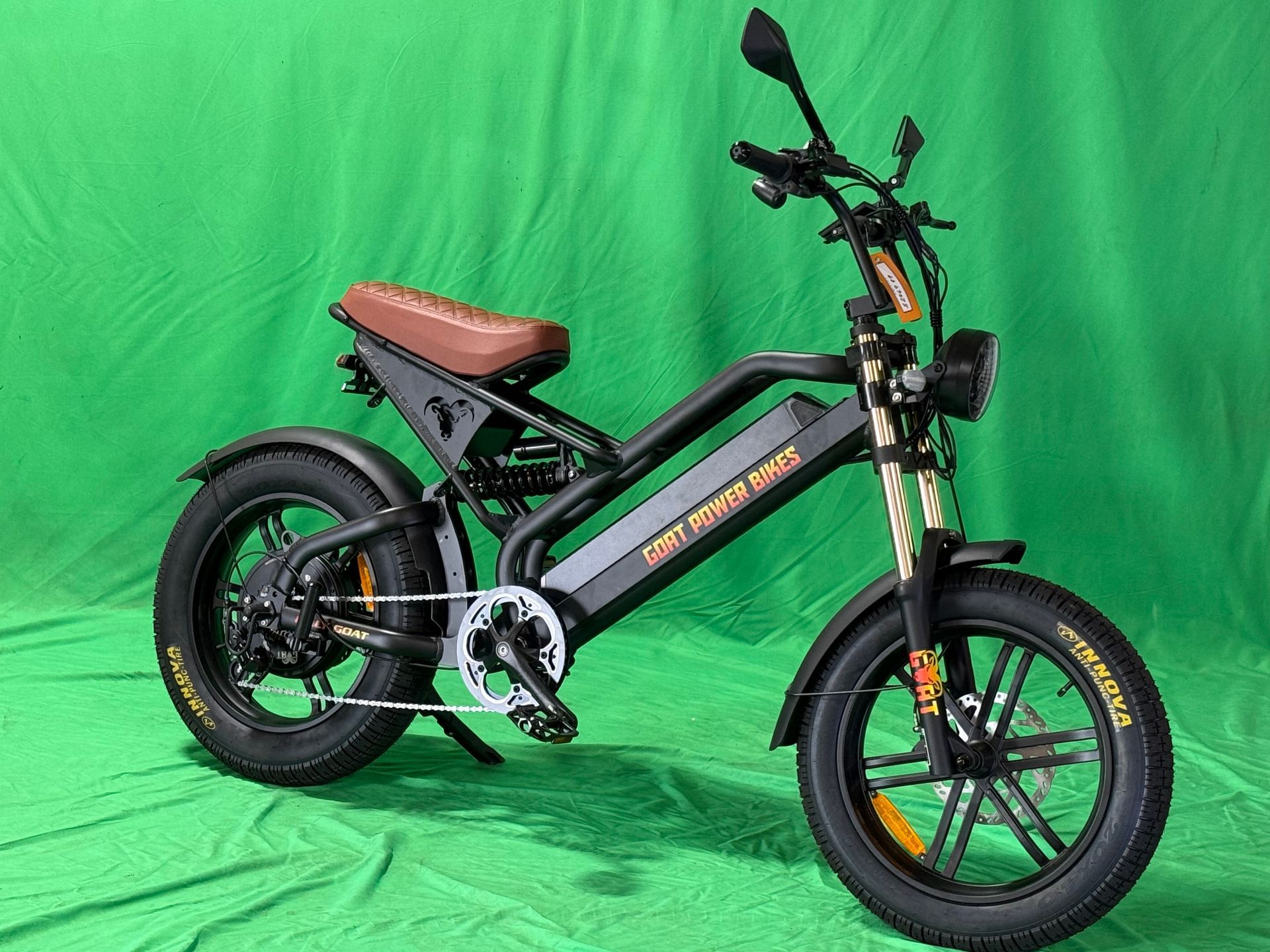 A black electric motorcycle is parked on a green background.