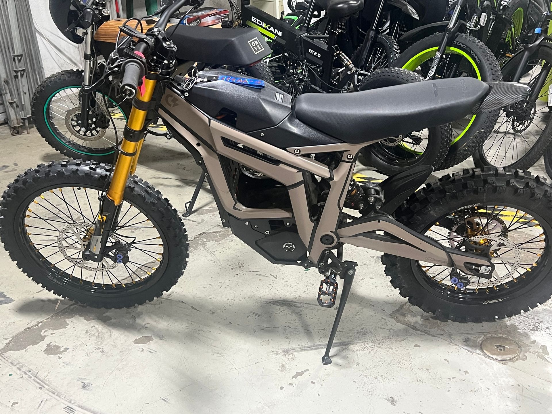 A dirt bike is parked in a garage next to other dirt bikes.