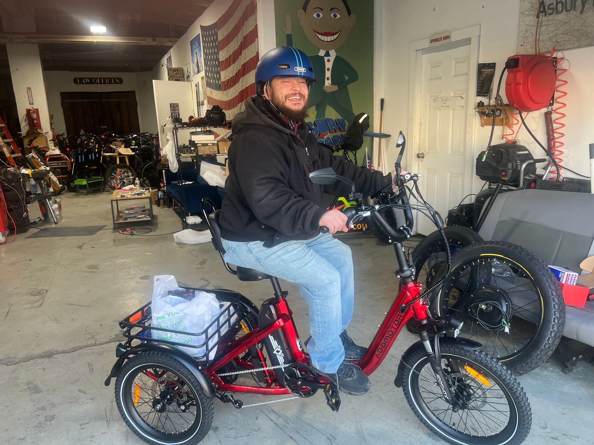 A man is riding an electric tricycle in a garage.