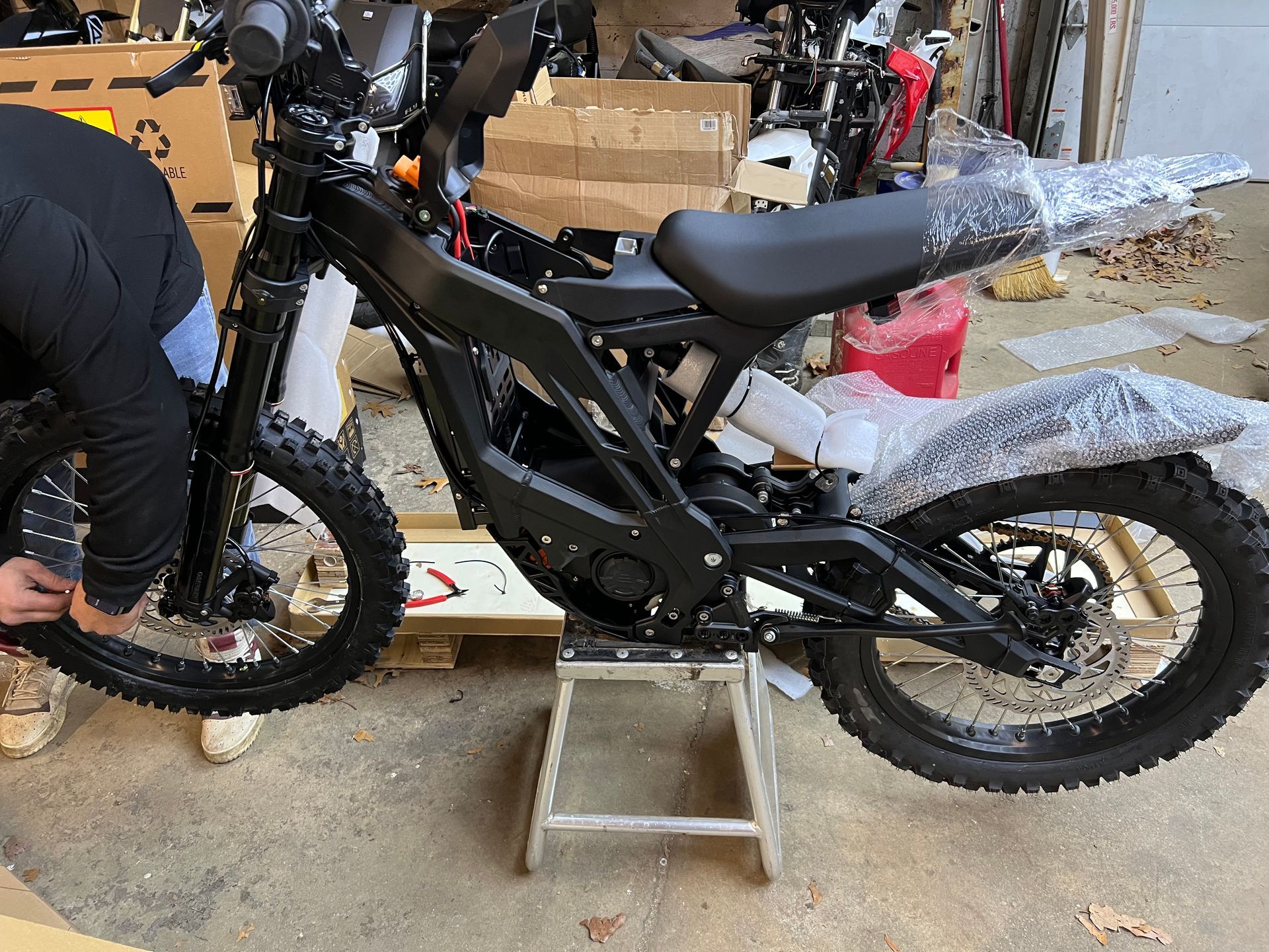 A man is working on an electric dirt bike in a garage.