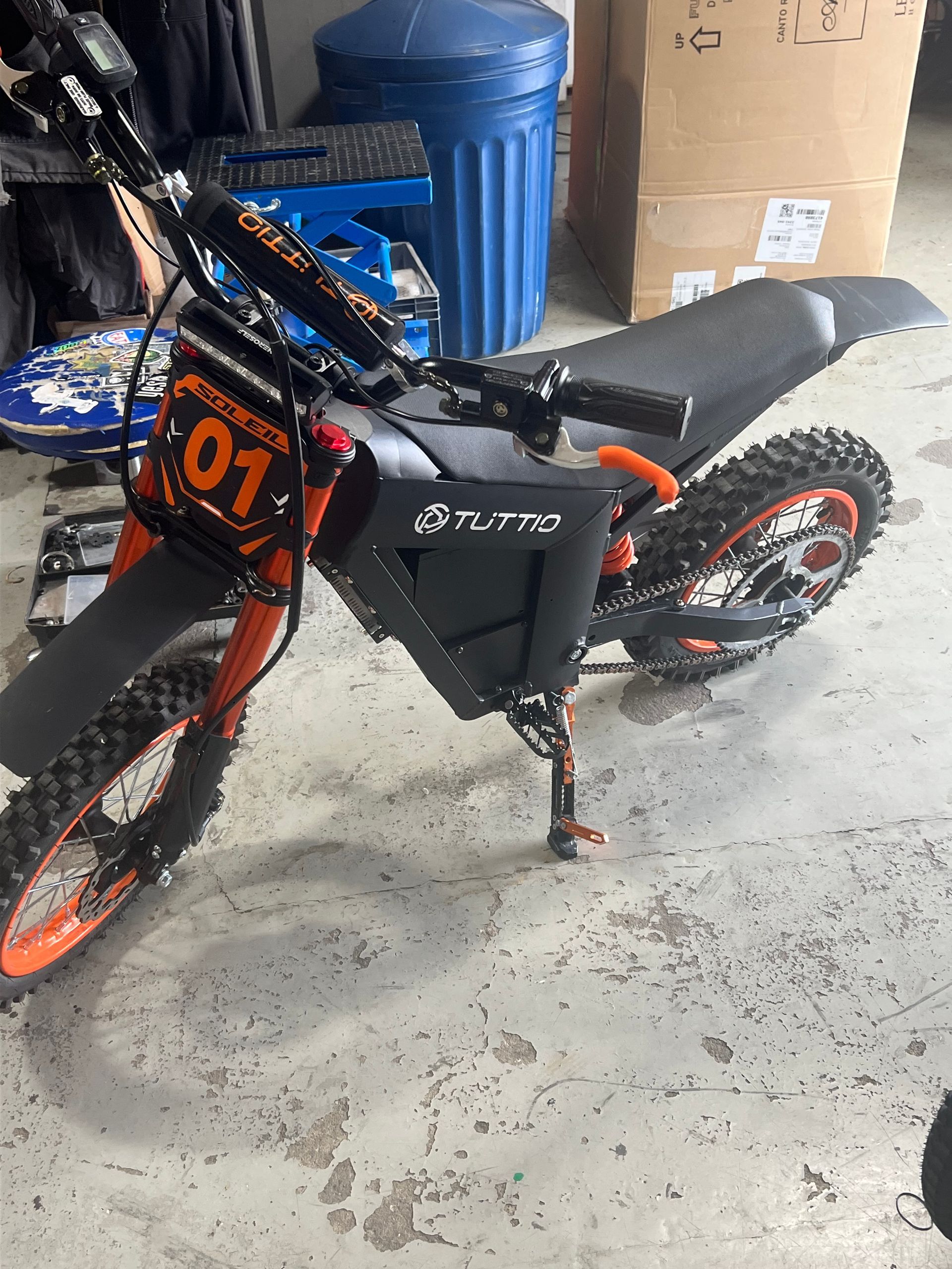 A dirt bike with the number 01 on the front is parked in a garage.