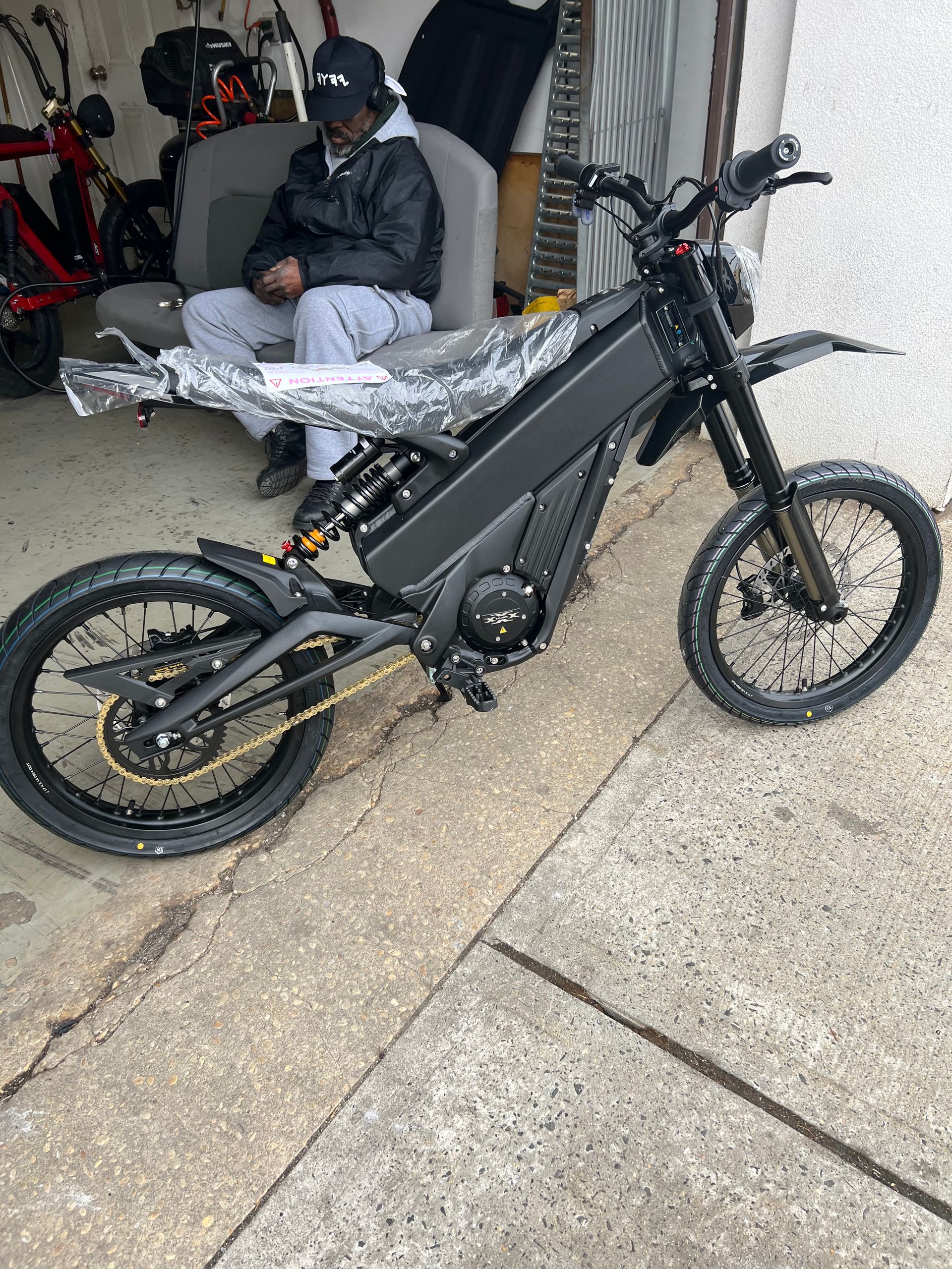 A man is sitting in a chair next to a black dirt bike.