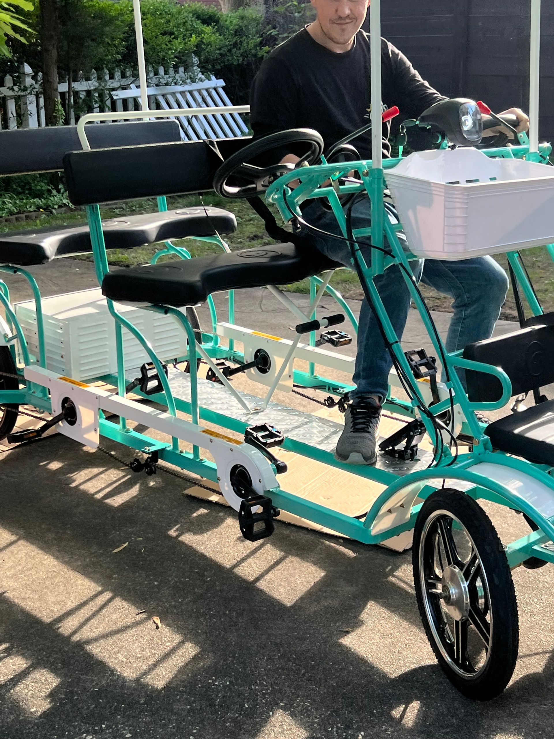 A man is sitting on a four wheeled bicycle.