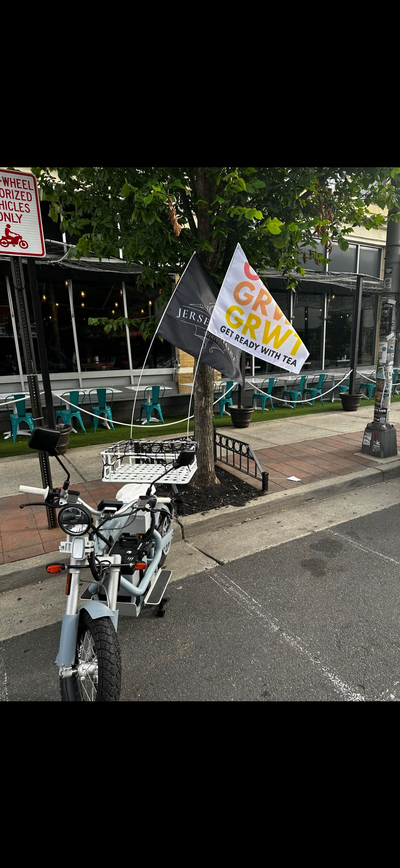A motorcycle is parked on the side of the road next to a tree.