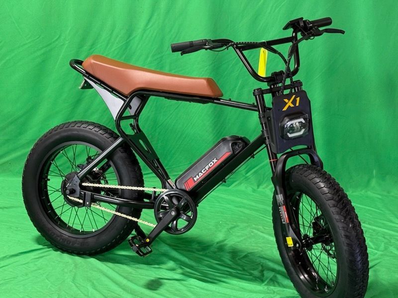 A black bicycle with a brown seat is sitting on a green cloth.