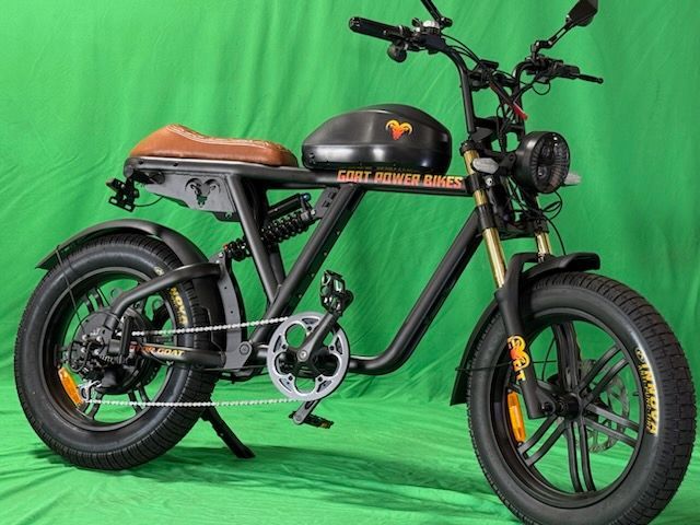 A black motorcycle is parked on a green background