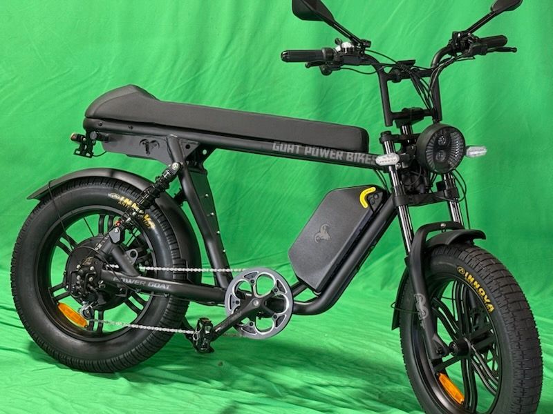 A black electric motorcycle is parked on a green background.
