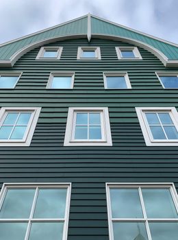 Looking up at a green building with lots of windows.
