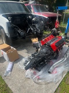 A red engine is sitting on the ground next to a white truck.