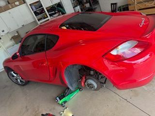 A red sports car is sitting on a green jack in a garage.