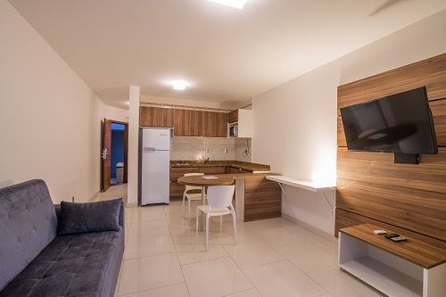Una sala de estar con sofá , televisión , mesa de comedor y sillas.