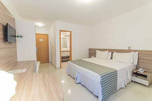 Una habitación de hotel con cama king size, escritorio y televisión.