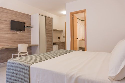 Una habitación de hotel con una cama grande y un televisor de pantalla plana.