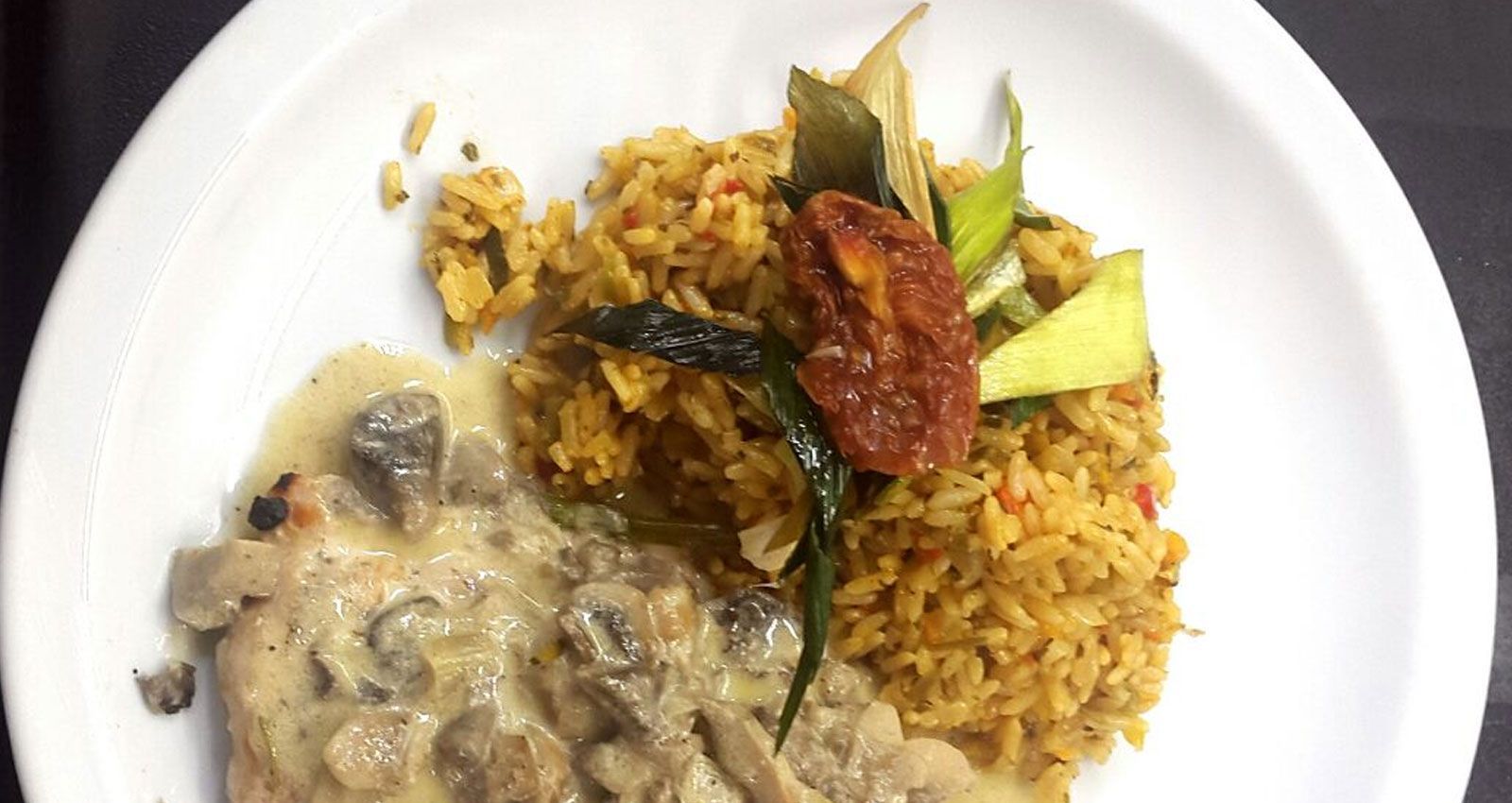 Un plato blanco cubierto con arroz, carne y verduras.