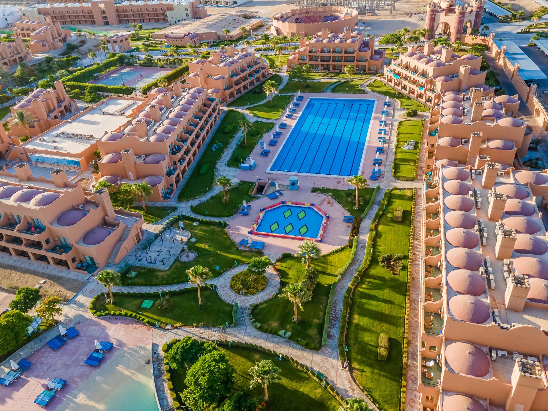 An aerial view of a large resort with a large swimming pool surrounded by buildings.
