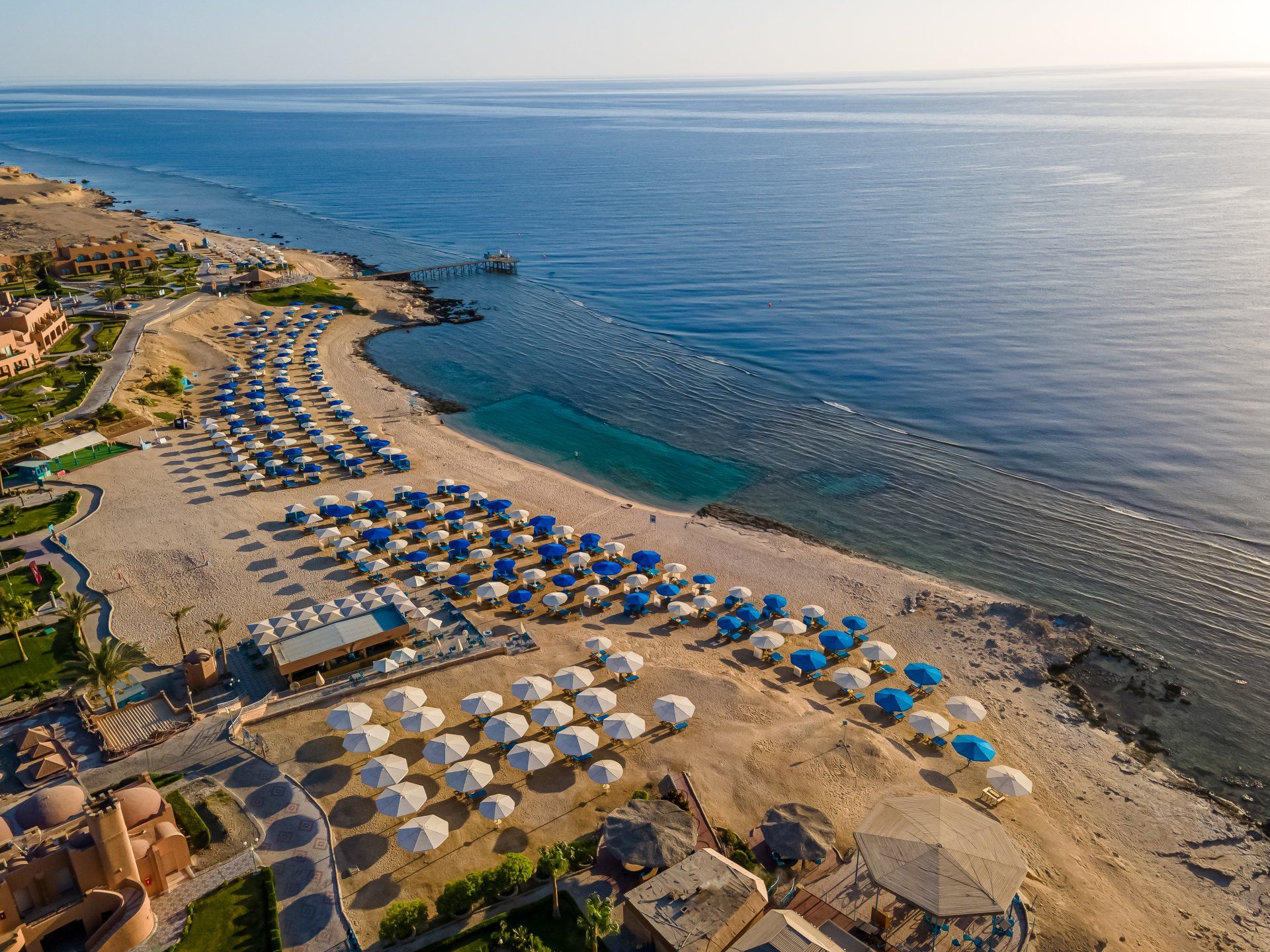 An aerial view of a beach with umbrellas and chairs.