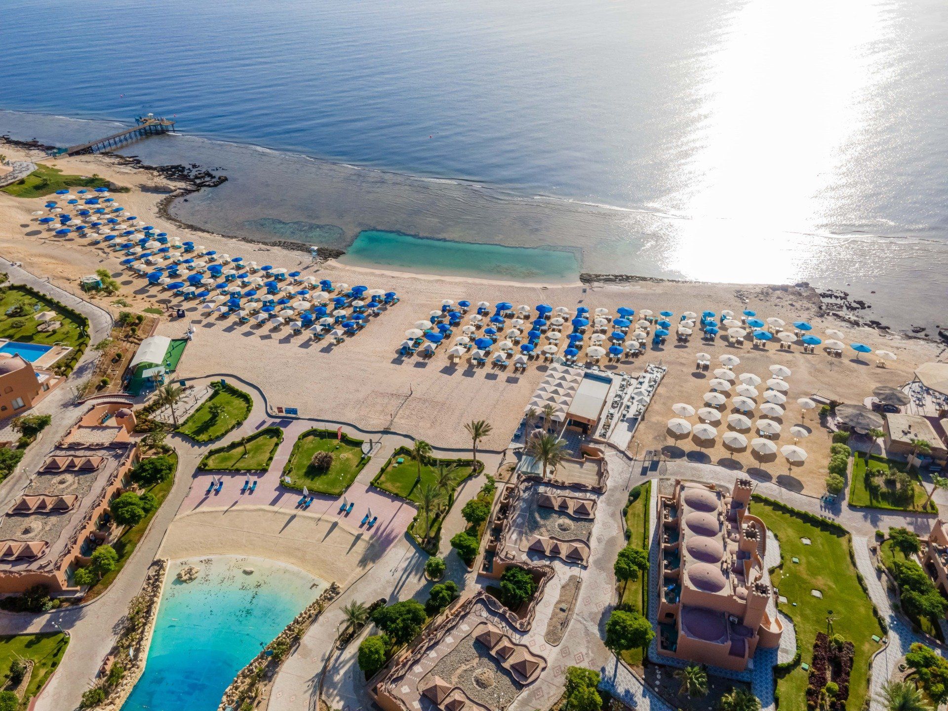 An aerial view of a beach with umbrellas and a pool.