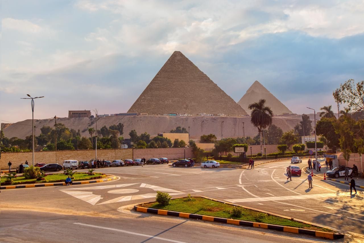 There are two pyramids in the background and a parking lot in the foreground.