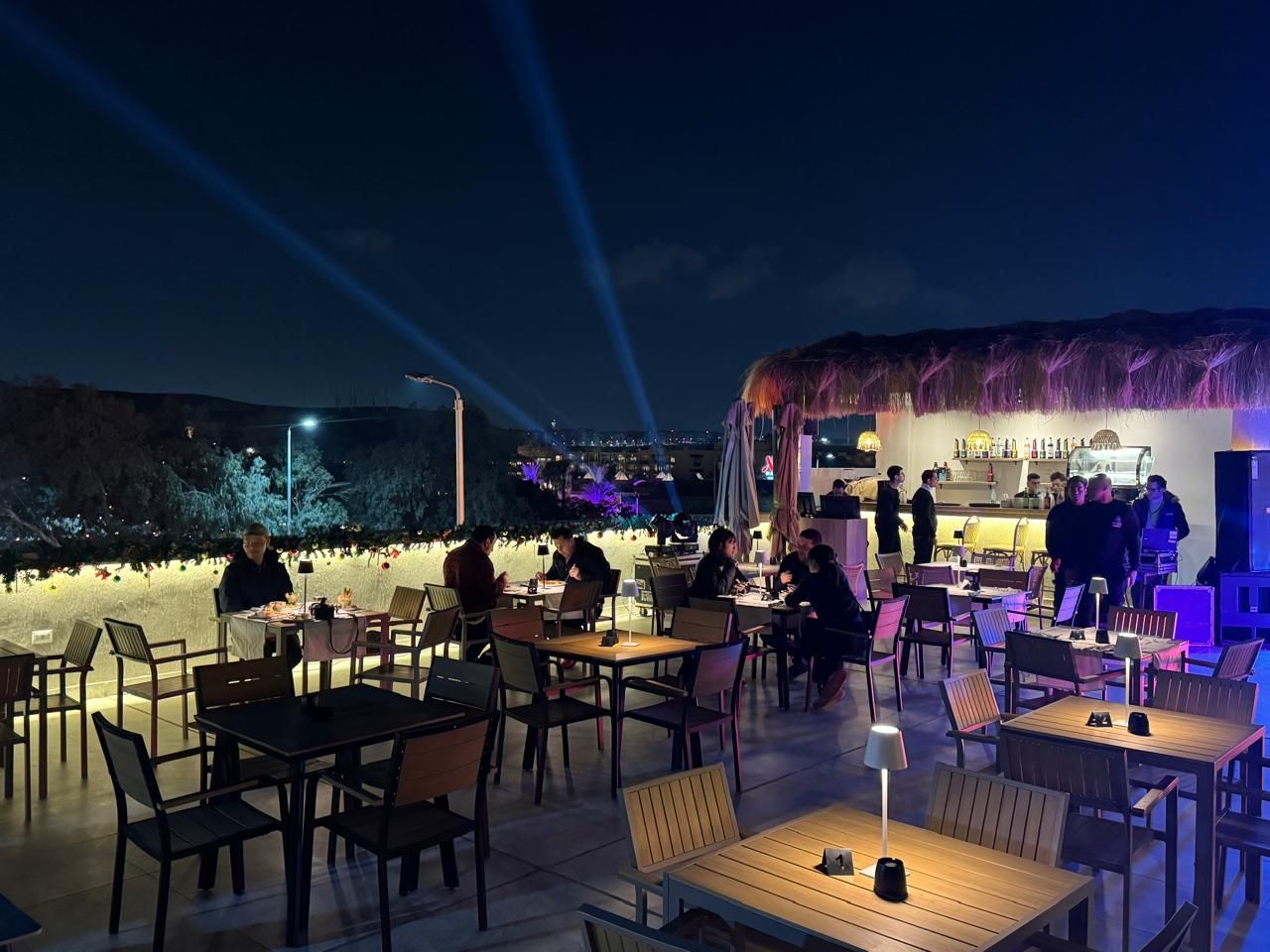 A group of people are sitting at tables in a restaurant at night.