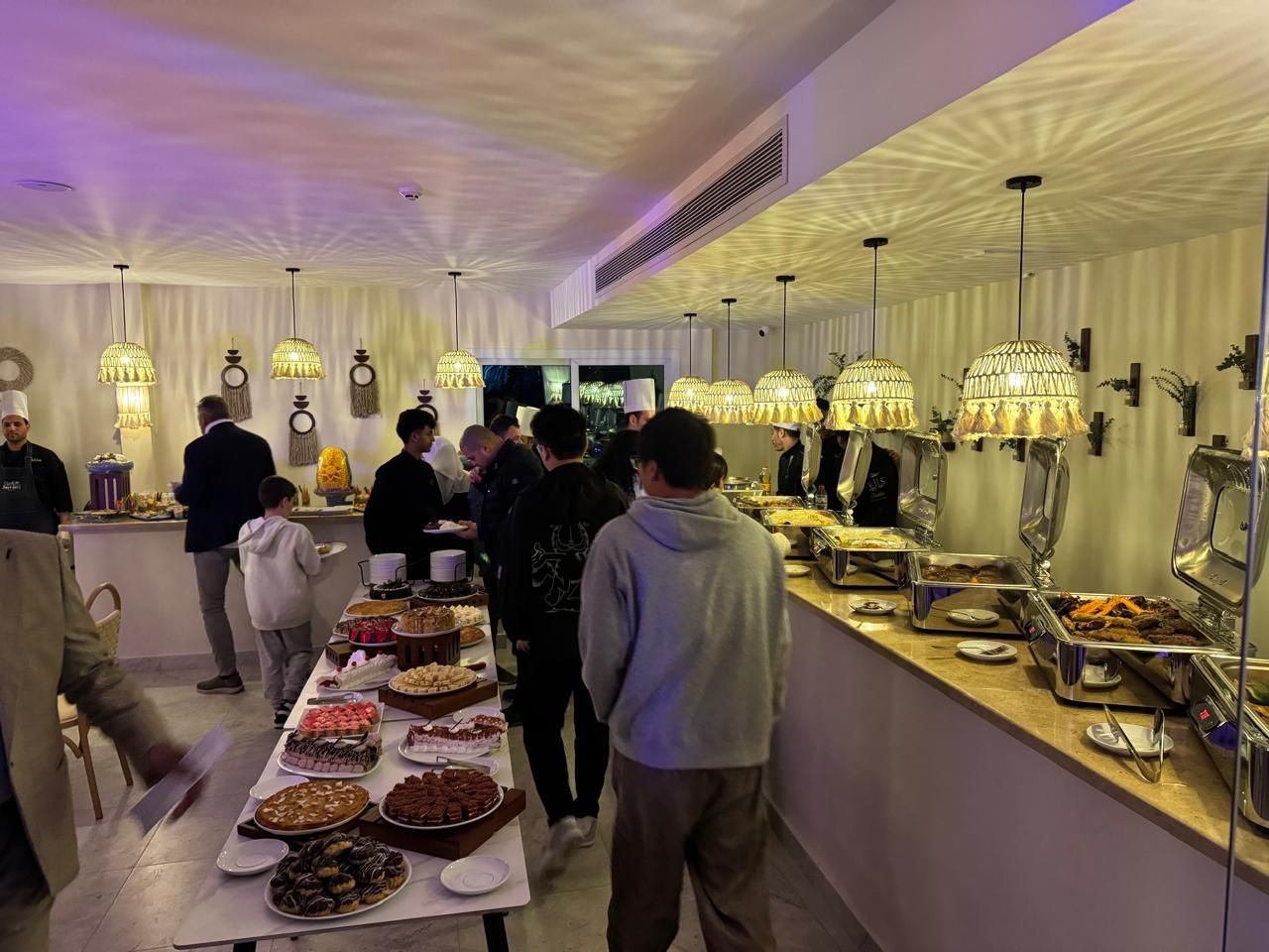 A group of people are standing around a buffet table in a restaurant.