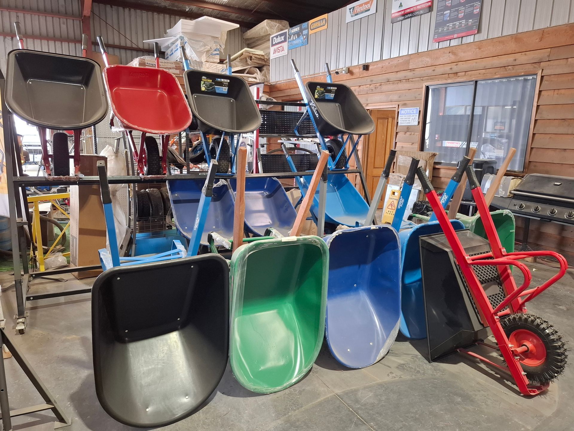 Rows of black and green wheelbarrows with yellow and white handles.