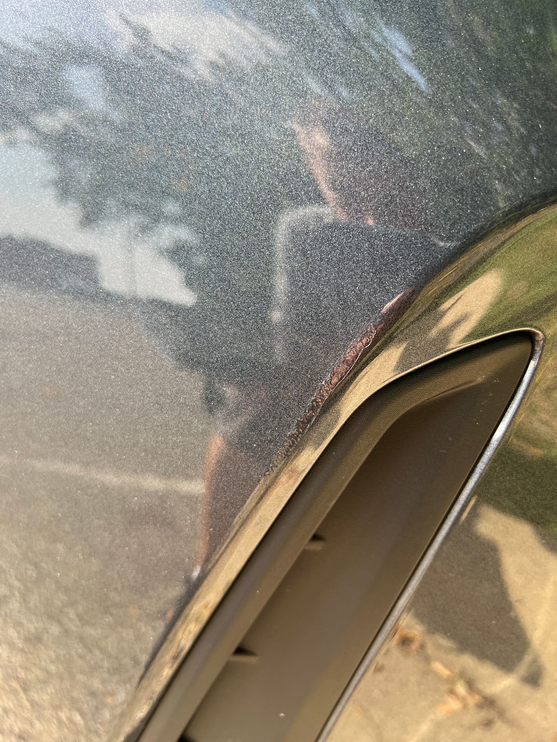 Close-up of a car's metallic grey paint and a black trim piece.