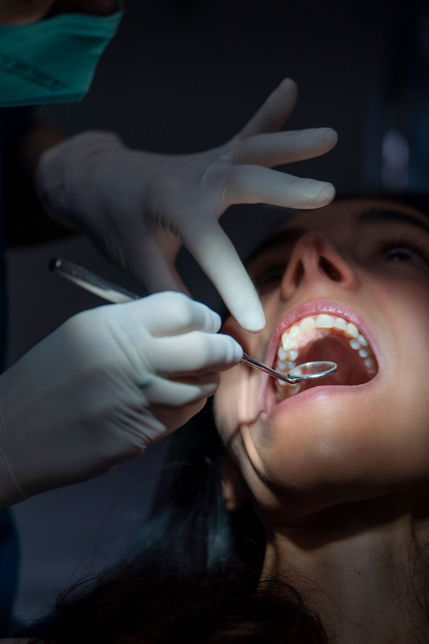 Dentist examining a woman's teeth in a dental office. Both are smiling.