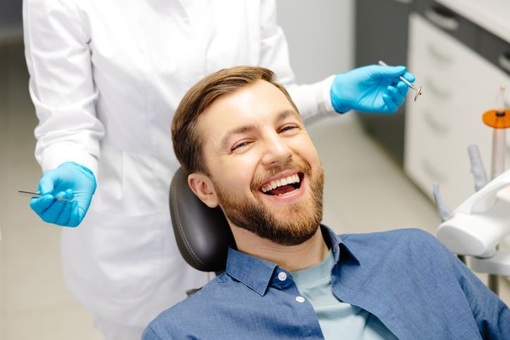 Dentist examining a patient's teeth with tools in a dental office.