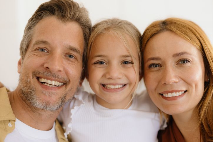 Dentist and patient smiling in a dental office. Woman in scrubs and older woman in chair.