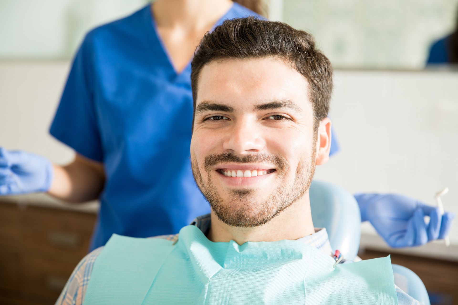 Dentist pointing at a dental X-ray, explaining it to a patient in a bright office.