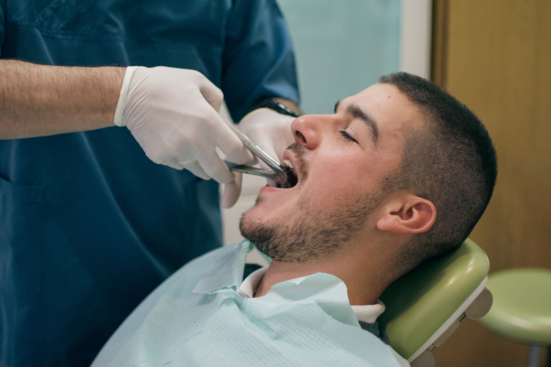 Dentist extracting a tooth from a patient's mouth in a dental office.
